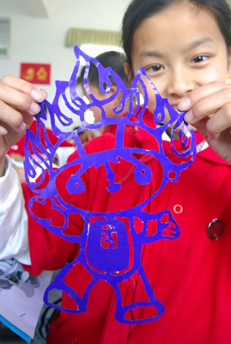 A pupil shows her paper-cut Fuwa Huan Huan, who symbolizes fire and is a mascot for the Beijing Olympic Games, in a Nanchang primary school in East China&apos;s Jiangxi Province, March 31, 2008. The school encouraged students to make Fuwa-themed paper-cuts to celebrate the upcoming Olympics. [Xinhua]