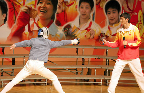 Olympic fencing champion Zhong Man gives instructions to a local resident in Hong Kong, August 30, 2008. China's Olympic gold medallists arrived in Hong Kong on Friday, kicking off their three-day visit to the city.[Xinhua]