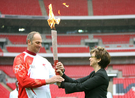 London Vice-Mayor Nicky Gavron (R) hands over the Beijing Olympic torch to quintuple Olympic gold medallist rower Steve Redgrave, who starts the Sundaly's relay in London, at Wembley Park, April 6, 2008. About 80 athletes and celebrities will carry the torch by foot, bike, boat and bus during the 31-mile relay. [Xinhua]