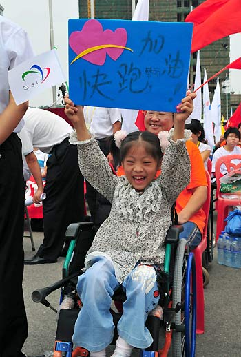 A local girl holds up a sign board to cheer on torch bearers during the Beijing Paralympic torch relay in Changsha, Hunan Province, August 31, 2008. [Xinhua]
