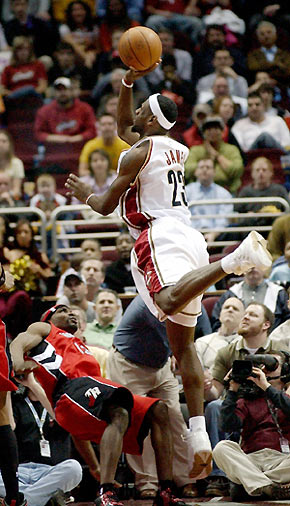 LeBron James (R) of the Cleveland Cavaliers is called for a charging foul as Mike James of the Toronto Raptors falls to the floor during the third quarter of their NBA basketball game in Cleveland, Ohio March 7, 2006. The Cavaliers won 106-99. [Reuters]