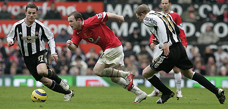 Manchester United's Wayne Rooney (C) runs passed Newcastle United's Scott Parker (L) and Peter Ramage (R) during their English Premier League soccer match at Old Trafford in Manchester, northern England, March 12, 2006. [Reuters]