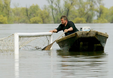 A man rows a boat at a flooded football field, near the Danube River, in the village of Ritopek near Belgrade April 17, 2006. The Danube peaked at record highs in Serbia on Monday without overwhelming flood defences, but authorities warned there was still danger waterlogged dykes could collapse and wreak havoc across southeastern Europe. [Reuters]