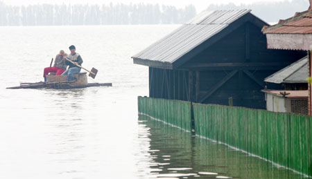 Two Romanians in a makeshift boat pass flooded houses by Danube river in Fetesti, 150 km (93 miles) east of Bucharest, Romania, April 17, 2006. The Danube peaked at record highs in Serbia on Monday without overwhelming flood defences, but authorities warned there was still danger waterlogged dykes could collapse and wreak havoc across southeastern Europe. 