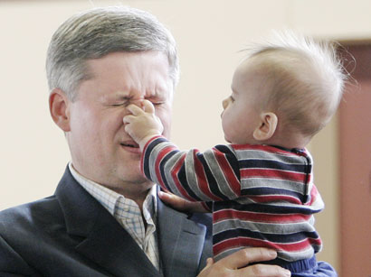 Prime Minister Stephen Harper (L) reacts as six-month-old Solomon Buster Sitar touches his nose during a visit to the Willingdon Heights Community Centre in Burnaby, British Columbia April 18, 2006. Harper held a roundtable meeting with parents to discuss his government's child care plan. 