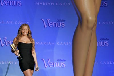 Singer Mariah Carey poses next to a sixteen foot high replica of her legs at Radio City Music Hall in New York May 30, 2006. Carey was appearing to promote the "Legs of a Goddess" contests, which will be held at select venues on Carey's concert tour. 