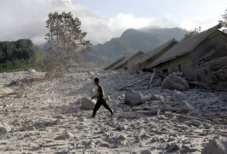 Villagers look at their house, which was filled by volcanic debris by the Mount Merapi volcano at a tourist spot, in the village of Kaliadem in the district of Sleman