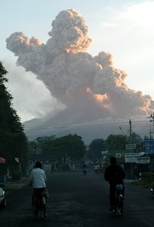 Villagers look at their house, which was filled by volcanic debris by the Mount Merapi volcano at a tourist spot, in the village of Kaliadem in the district of Sleman