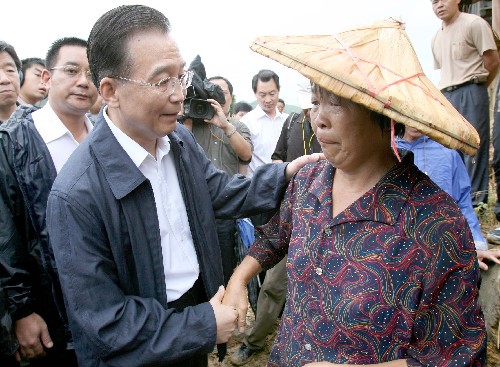Chinese Premier Wen Jiabao talks to a farmer at a flood-hit village in Longyan City, East Chinas Fujian Province, June 27, 2006. Since mid-May, Fujian has been devastated by typhoon- and rainstorm-caused floods, leaving at least 25 deaths and five missing and causing enormous financial losses.[Ma Zhancheng/Xinhua]