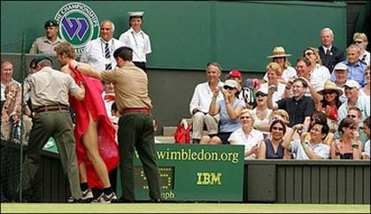A streaker, surrounded by security men, leaves center court as Maria Sharapova of Russia plays against compatriot Elena Dementieva in the quarter-finals the Wimbledon Tennis Championships. The streaker was identified as a Dutch DJ who reportedly carried out the stunt for a television programme.[AFP]