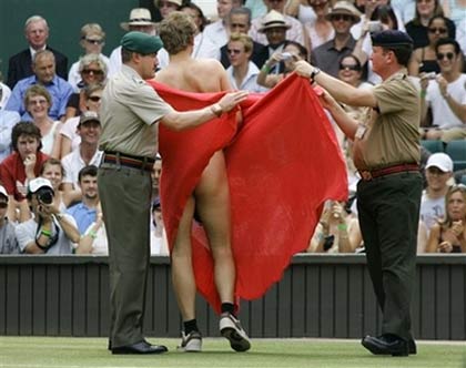 An unidentified streaker is escorted sway by military stewards, after interrupting the Women's Singles quarter-final match between Maria Sharapova and Elena Dementieva, both of of Russia, on the Centre Court at Wimbledon, Tuesday, July 4, 2006.[AP Photo]