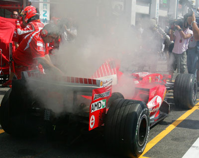 Mechanics extinguish a fire on the Ferrari driven by Formula One driver Michael Schumacher of Germany during the third free practice session of the French Grand Prix at the Magny-Cours circuit July 15, 2006. The French Grand Prix will take place on Sunday July 16, 2006.