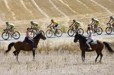 Phonak's team rider Floyd Landis of the U.S. (C), wearing the leader's yellow jersey, and his team mates cycle past two spectators on horseback during the 12th stage of the 93rd Tour de France cycling race between Luchon and Carcassone, July 14, 2006.[Reuters]