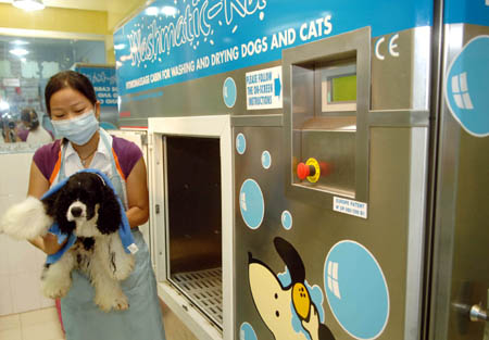 An employee takes a dog out of a pet-bathing machine at a pet beauty center in Wuxi July 21, 2006. Pets can receive various services such as washing, drying, disinfecting and spraying fragrance in the machine introduced by the center. [Xinhua]