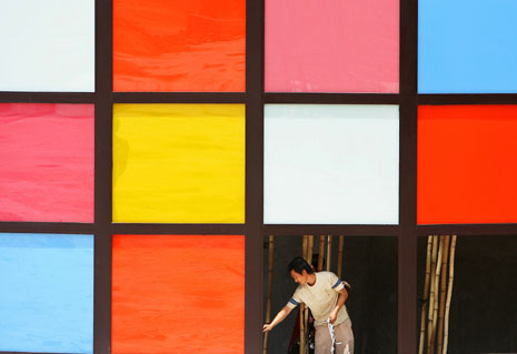 A labourer fixes glass windows at a construction site in Haikou, southern China's Hainan province August 5, 