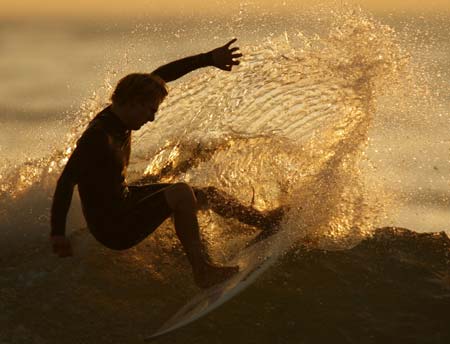 A surfer is silhouetted as he cuts a turn on a wave during a summers evening on the Pacific Ocean in Solana Beach, California August 8, 2006. 