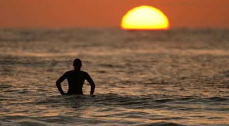 A surfer is silhouetted as he cuts a turn on a wave during a summers evening on the Pacific Ocean in Solana Beach, California August 8, 2006. 