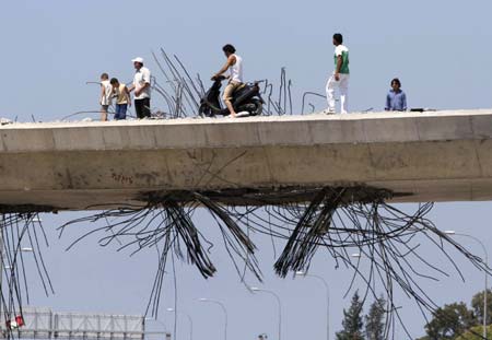 People cross a damaged bridge in Zahrani, south Lebanon August 14, 2006. Guns fell silent across southern Lebanon on Monday after a U.N.-brokered truce went into effect to end five weeks of fighting between Israel and Hizbollah that killed more than 1,250 people and wounded thousands. 