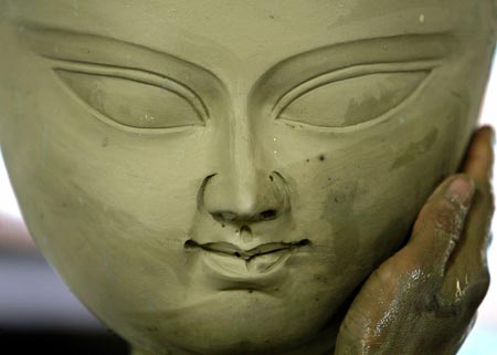 An artisan gives the finishing touches to the face of Hindu deity Durga at a workshop in the northeastern Indian city of Siliguri August 28, 2006. 