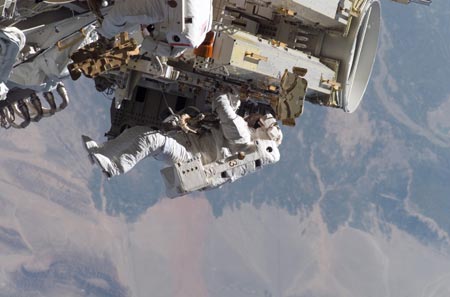 Astronaut Heidemarie Stefanyshyn-Piper releases the restraints on the forward Solar Array Blanket Box (SABB) during a spacewalk with astronaut Joseph Tanner (partially visible at top edge of frame) September 12, 2006. 