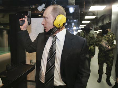 Russian President Vladimir Putin stands with a gun at a shooting gallery of the new GRU military intelligence headquarters building as he visits it in Moscow November 8, 2006. 