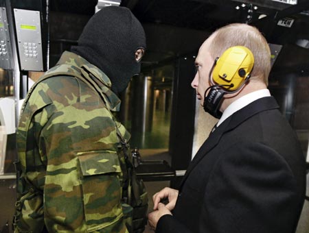 Russian President Vladimir Putin (R) and a masked security officer stand at a shooting gallery of the new GRU military intelligence headquarters building as he visits it in Moscow November 8, 2006. 