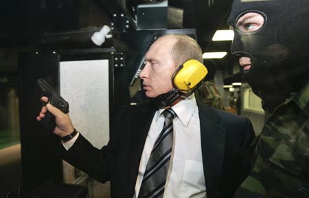 Russian President Vladimir Putin (L) and a masked security officer stand at a shooting gallery of the new GRU military intelligence headquarters building as he visits it in Moscow November 8, 2006.