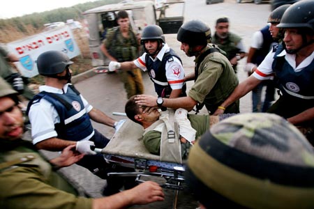 Israeli soldiers evacuate a wounded comrade near the Israeli town of Avivim, along the Israel-Lebanon border July 20, 2006. Hizbollah fought fierce battles with Israeli troops on the Lebanese border on Thursday, as thousands more foreigners fled the nine-day-old war in Lebanon, including 1,000 Americans evacuated by U.S. Marines. 