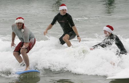 Henrik Sorli (L), Klaus Roberg and Oystein Kaasa (R) of Norway wear Santa Claus hats as they try surfing at Manly Beach in Sydney December 24, 2006. 