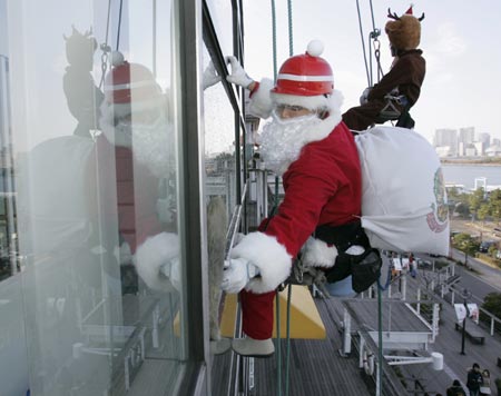 Window washers dressed as Santa Claus and a reindeer work at a shopping mall in Tokyo December 24, 2006. 