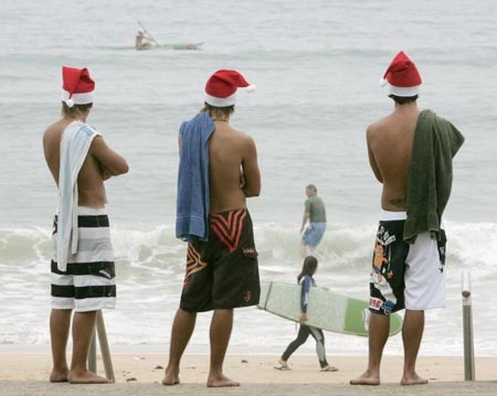 Beach goers wearing Santa Claus hats survey conditions before swimming at Queenscliff Beach in Sydney December 24, 2006. 