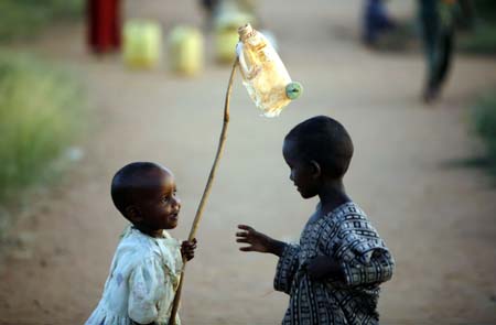 Two Somali child refugees play with a toy improvised from a plastic bottle at Ifo camp near Dadaab, northeastern Kenya, January 6, 2007. The UNHCR operates three large refugee camps in northern Kenya at Dadaab, some 80 km (50 miles) from Liboi, where about 160,000 Somali refugees are held. It said it could provide more staff to help Kenya with any new influx. 