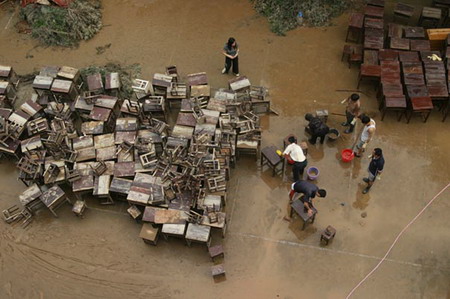 Teachers clean school desks and chairs after a flood at a school in Jianou city, East China's Fujian Province, June 9, 2006. Some 80 percent of the city was submerged by the flood. [Xu Yimin/ Southeastern Express]