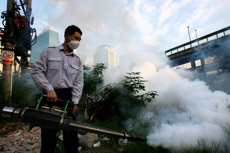 A health worker tries to smoke away mosquitoes during a campaign to control the outbreak of dengue fever in Guangzhou, South China's Guangdong Province, September 1, 2006. [Ning Biao/New Express]