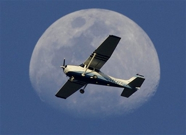 A single engine plane passes under a waxing 3/4 moon late Tuesday, Feb. 27, 2007, over Ormond Beach. Fla. 