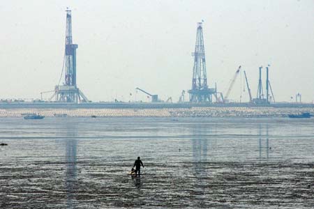 A labourer walks toward the Jidong Nanpu oilfield in Bohai Bay of north China's Hebei province May 10, 2007. China's newly found oilfield in Bohai Bay has a reserve of one billion tons, or about 7.35 billion barrels, the largest discovery in the country over four decades, announced the China National Petroleum Corporation, Xinhua News Agency reported. Picture taken May 10, 2007. 