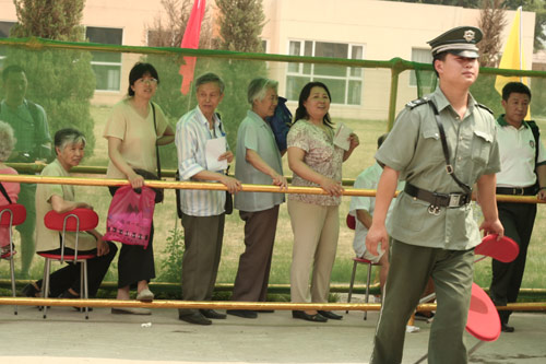 A security man carries a charir at the venue for a vote on demolishment and reconstruction of old buildings in Juixiaqiao Sub-district in Beijing, June 9, 2007. Local government and the real estate developer jointly organize the vote on Saturday to see if majority residents of over 5000 families accept the new compensation policy after failed attempts to reach an agreement through other ways. Both notary officials and supervisors are invited to monitor the vote that runs from 9 a.m. to 9 p.m. at six ballot booths. [Sun Yuqing/www.chinadaily.com.cn]