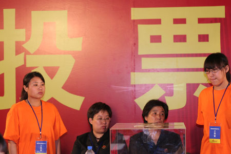 Two notary officials in black uniform and two voting workers wait to count the votes after a voting on the housing demolition and compensation policy at Jiuxianqiao sub-district in Chaoyang District of Beijing, June 9, 2007. Some 3,711 families, about 57% of the 5,473 families, cast their votes on Saturday, with 2,451 votes for and 1,228 votes against the demolition and compensation plan. Thirty-two votes were invalid. 