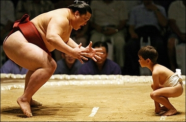 Sumo in training : A young boy (R) lines up against a professional sumo wrestler (L) during an exhibition before the start of the first day of the Grand Sumo Tournament in Hawaii 2007, at the Neil S. Blaisdell Arena in Honolulu, Hawaii.(AFP/Gabriel Bouys) 