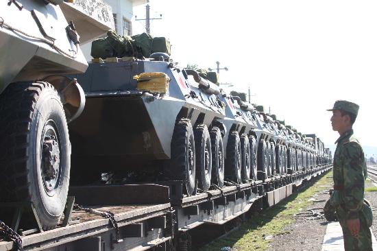 A Chinese soldier stands guard as military vehicles are transported by railway for the exercise of 