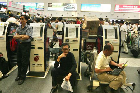 Passengers wait after their flights are canceled or delayed for the heavy rain at Capital International Airport in Beijing July 31, 2007. [CFP]
