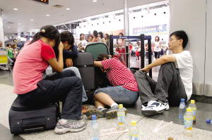 Passengers wait after their flights are canceled or delayed for the heavy rain at Capital International Airport in Beijing July 31, 2007. [Zhang Mo/Beijing Times]