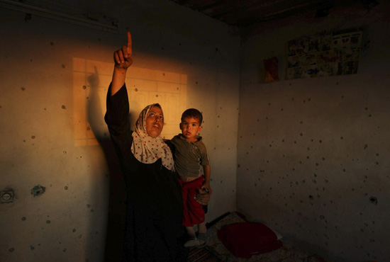 Palestinian woman in damaged house