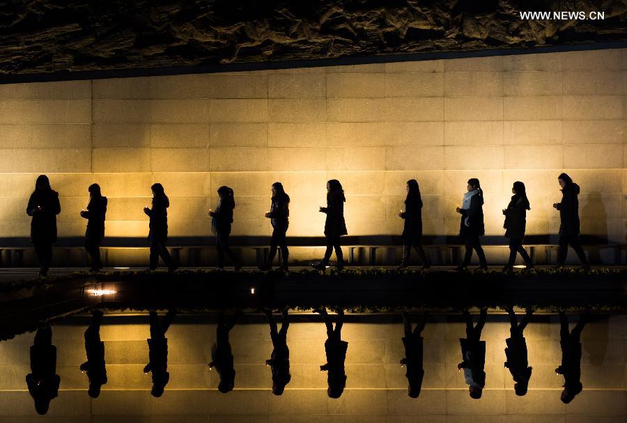 People hold candles to mourn victims of Nanjing Massacre