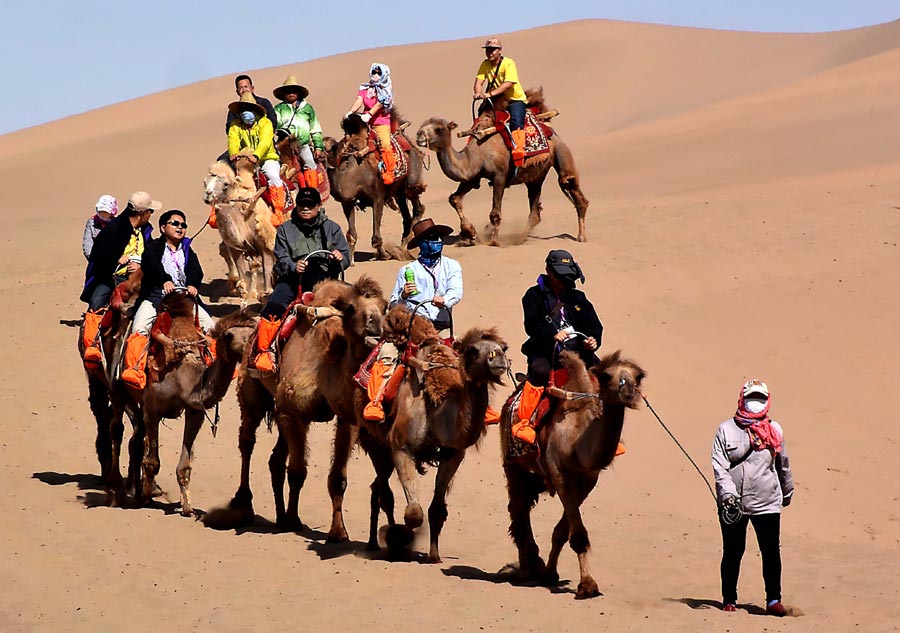 Tourists enjoy themselves at Mingsha Hill desert