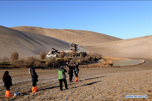 Tourists visit crescent spring of Mingsha Hill in Dunhuang