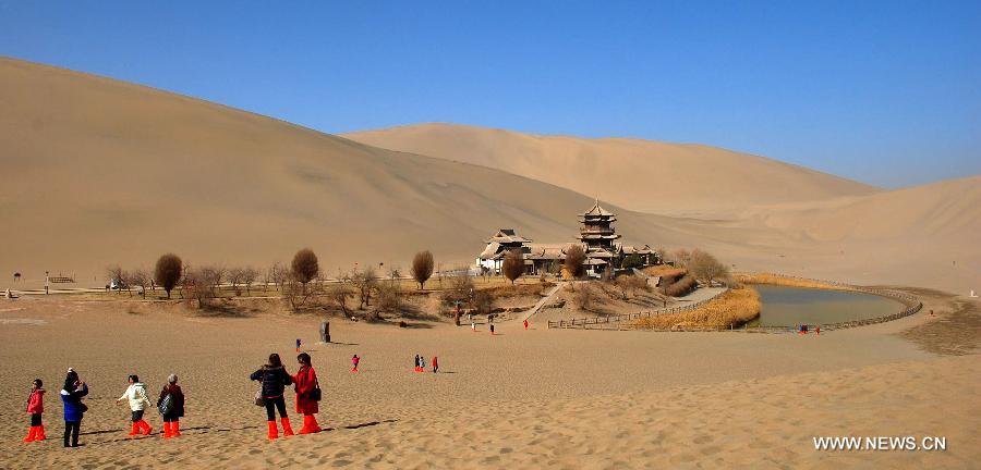 Tourists visit Crescent Moon Spring by camels