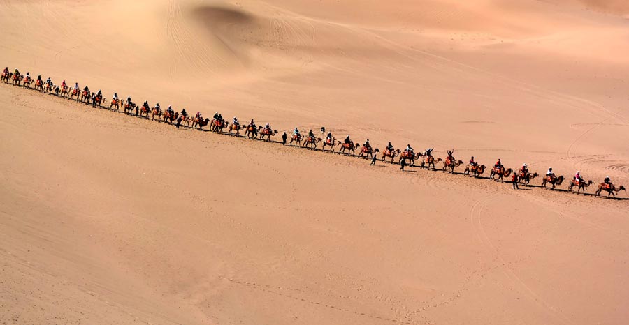 Tourists enjoy themselves at Mingsha Hill desert