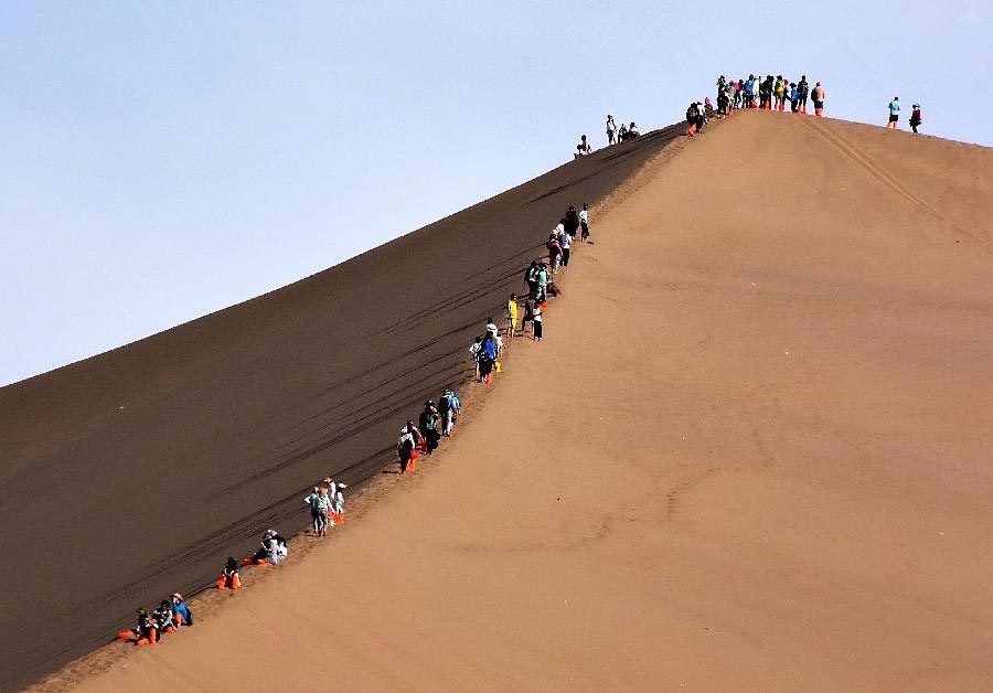 Tourists enjoy themselves at Mingsha Hill desert