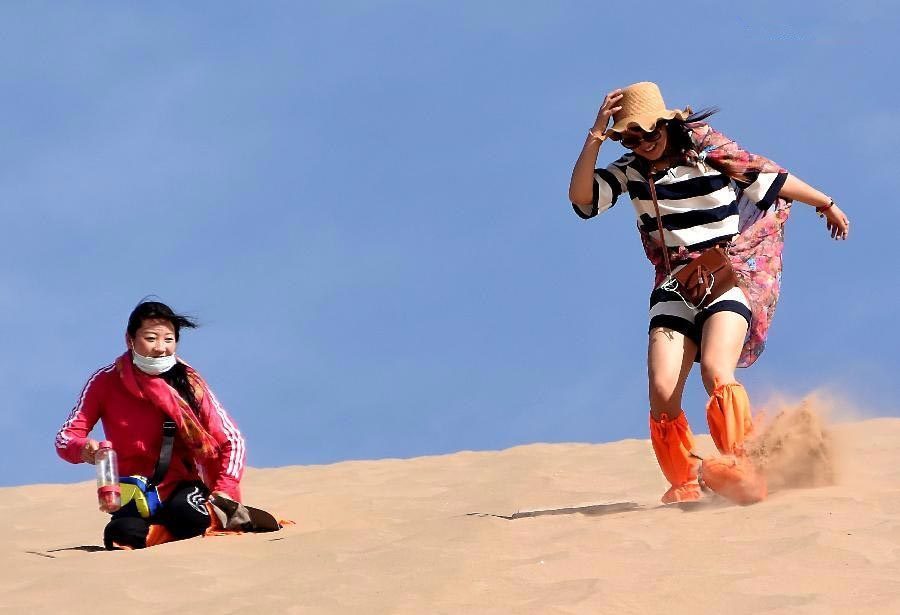 Tourists enjoy themselves at Mingsha Hill desert